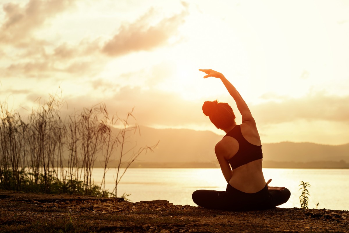 Mujer joven practicando yoga en la playa