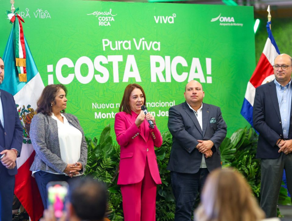 Mujer de traje rojo en una conferencia de prensa junto a cuatro personas